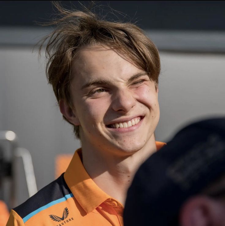 a smiling young man wearing an orange shirt