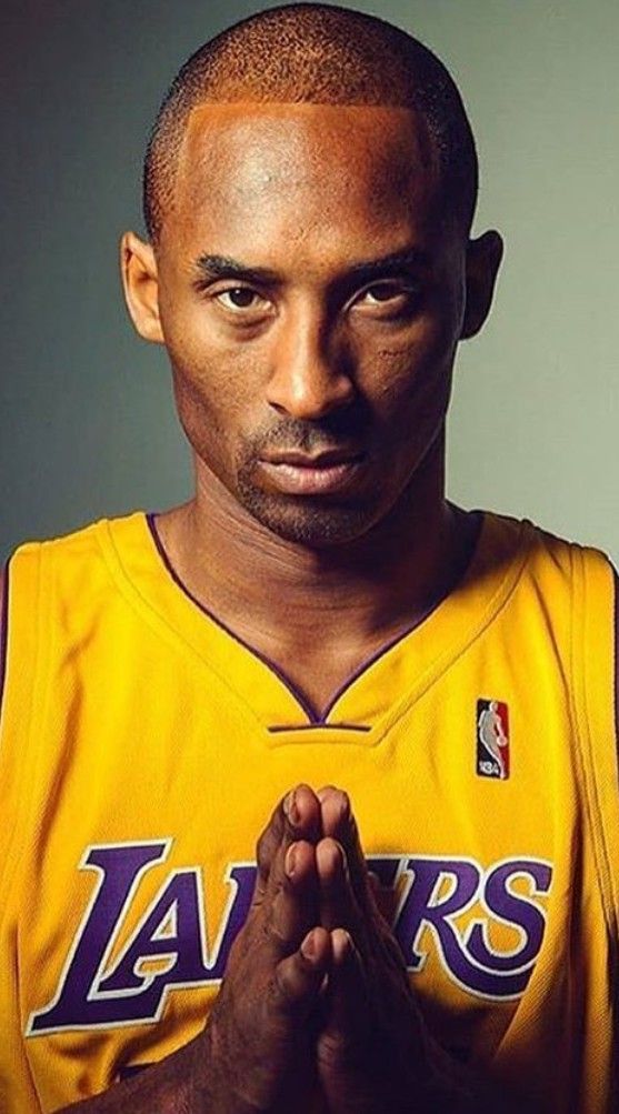 a man in a lakers jersey holding his hands together and looking at the camera with an intense look on his face