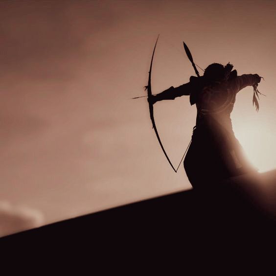 the silhouette of a man with an arrow in his hand, standing on top of a hill