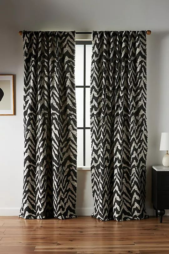 a black and white curtain hanging in front of a window next to a wooden floor