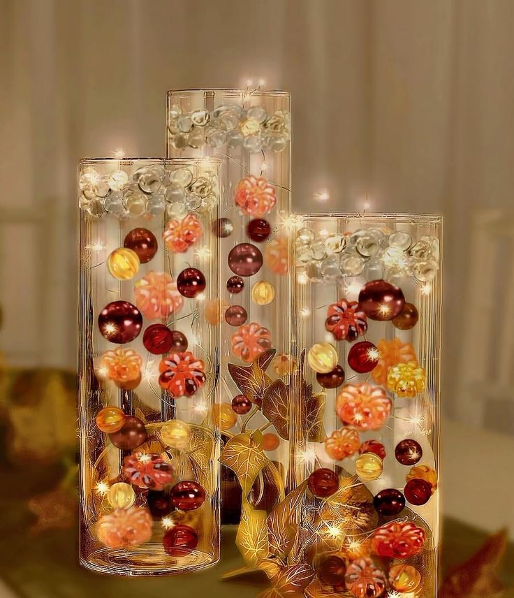 two vases filled with different types of glass beads and flowers on top of a table