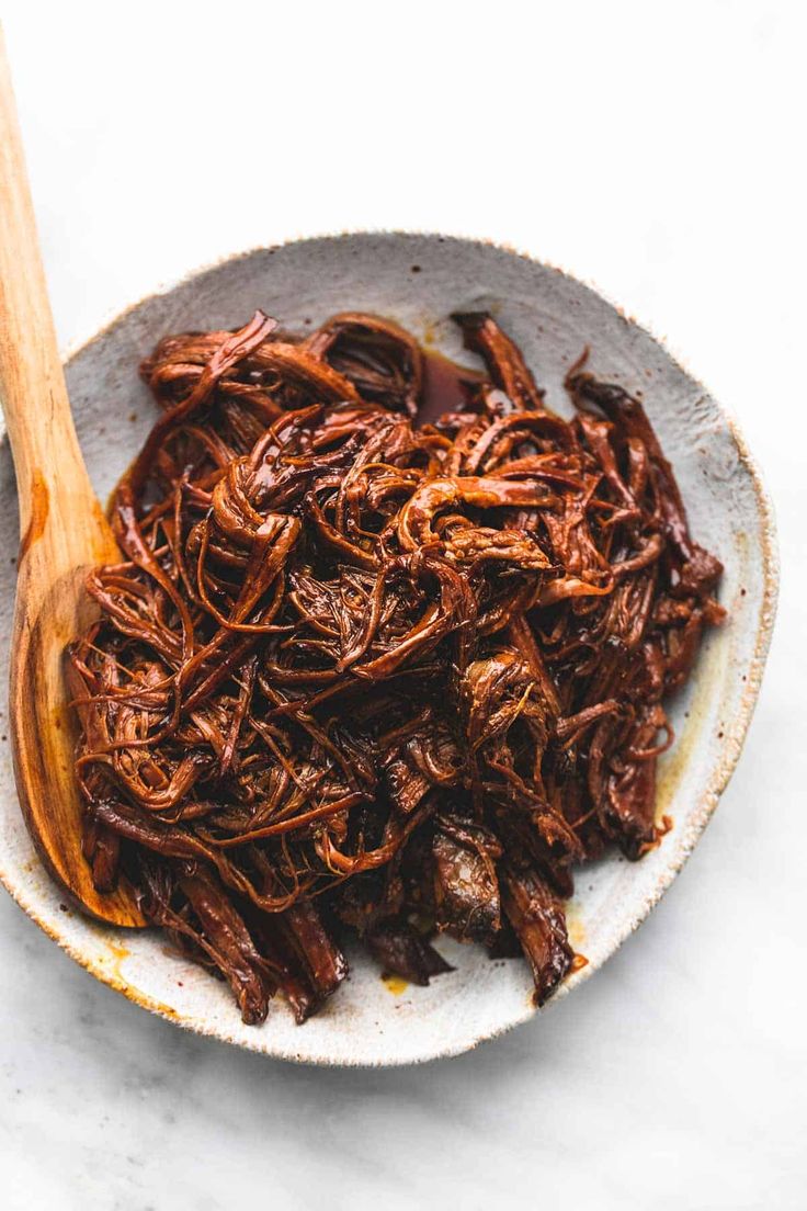 shredded beef in a bowl with a wooden spoon