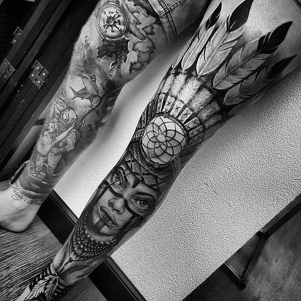 a man's leg with tattoos and feathers on it