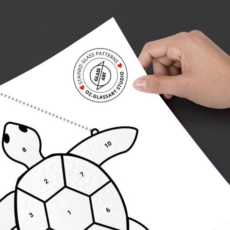 a hand holding a piece of paper with a drawing of a turtle on it