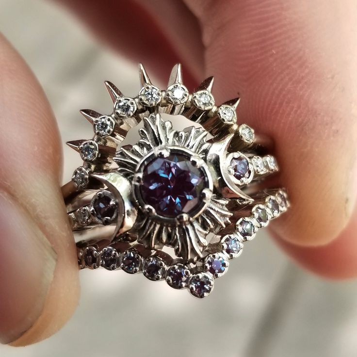 This engagement ring has a gorgeous approx. .65 carat color change Chatham Alexandrite in the center. Next to the center stone is a pair of crested crescent moons, nestled into each one is a 2mm Chatham Alexandrite, they have a combined weight of approx. .08 carats. On the band is 4 additional tiny white diamonds, they are VS clarity and G-H in color, they have a combined approx. weight of .03 carats. The top sunray band is set with approx. .07 carats of VS white diamonds and the bottom chevron Witchy Engagement Ring, Moon Engagement Ring, Chatham Alexandrite, Moonstone Engagement Ring Set, Gothic Engagement Ring, Ring Inspo, Moon And Star Ring, Moonstone Engagement Ring, Triple Moon