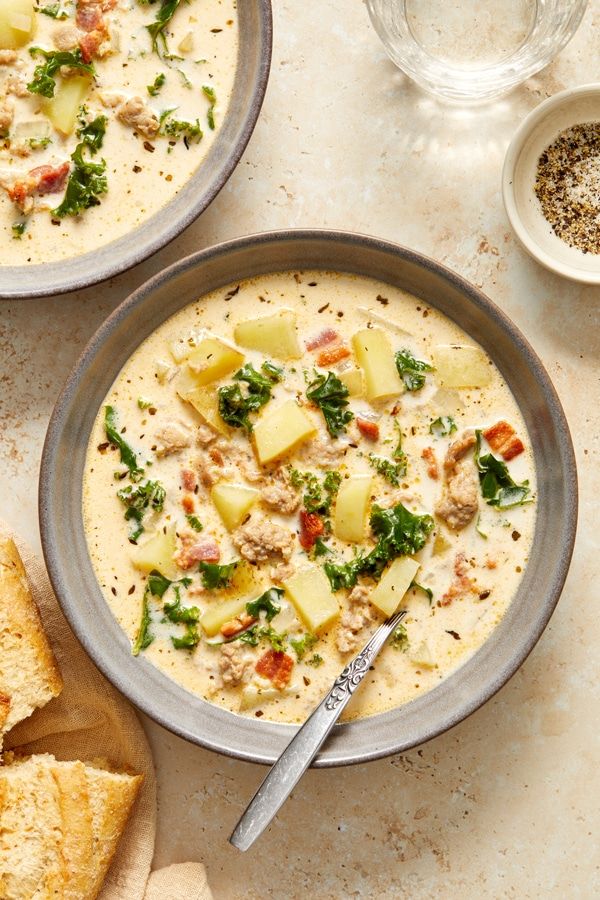 two bowls of soup with bread on the side