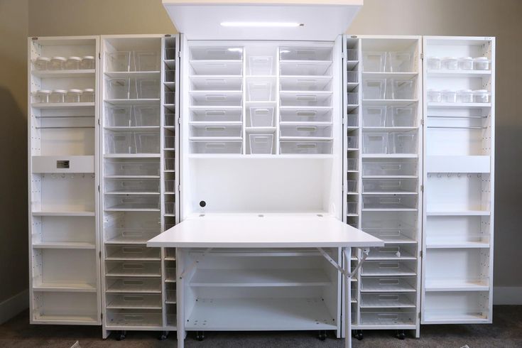 an office desk and shelves in the middle of a room with carpeted flooring