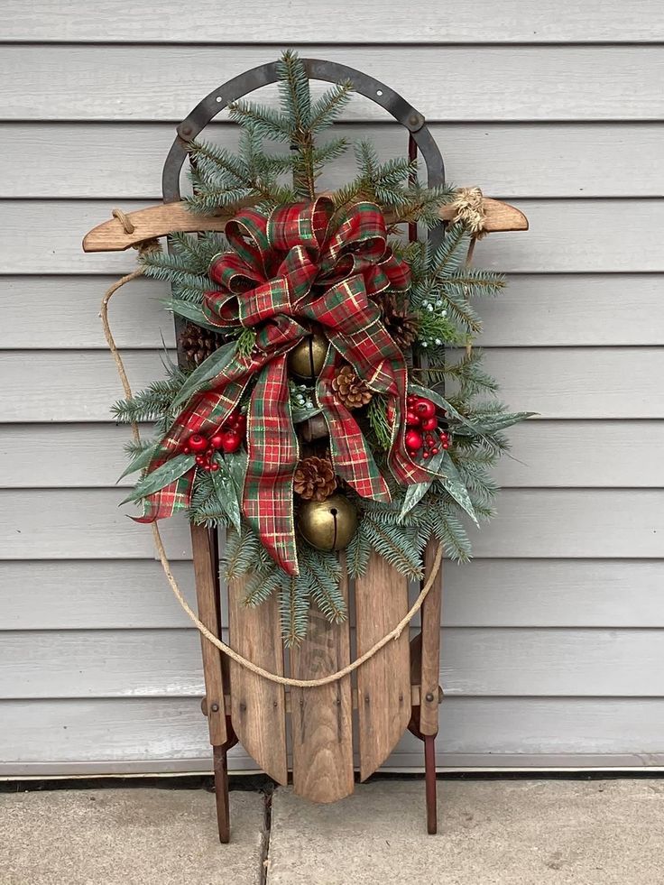 a wooden sled with christmas wreaths and bells hanging from it's side