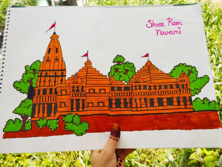 a hand holding up a drawing in front of some trees and buildings with the words shriree ram navami written on it