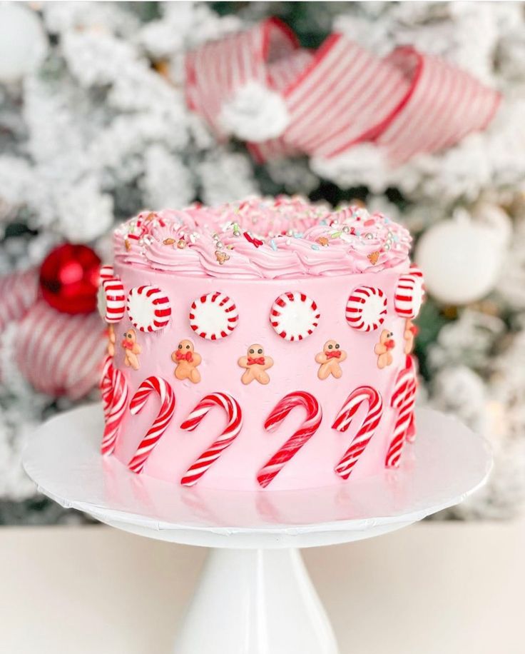 a pink christmas cake with candy canes and candies