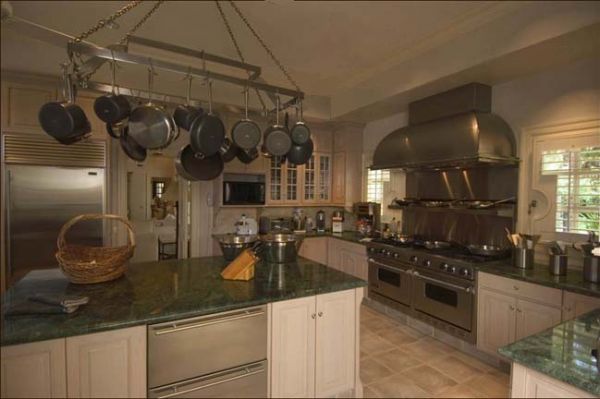 a large kitchen with many pots and pans hanging from the ceiling over the stove