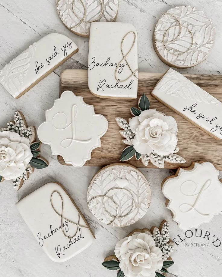 wedding cookies decorated with white flowers and names on wooden trays for the bride and groom