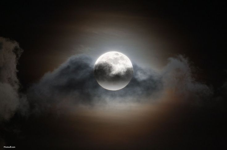 the full moon is seen through some clouds