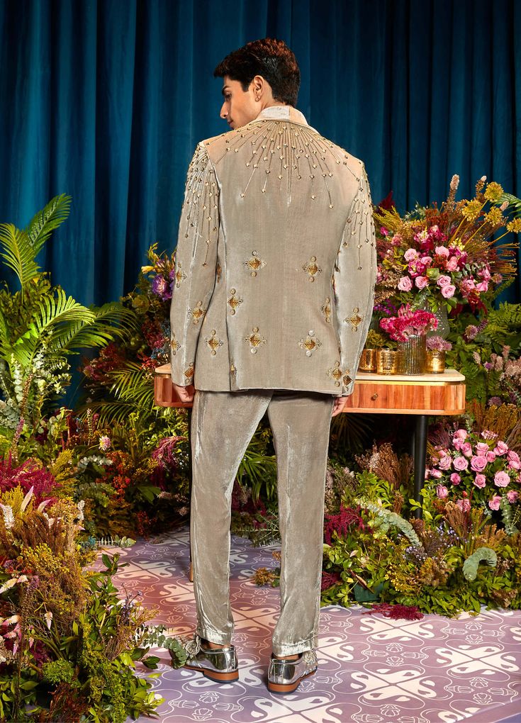 Look dapper for your cocktail night in a velvet blazer adorned with metal embellishments paired with an ivory shirt complete your look with grey velvet pants. Velvet Sherwani For Men, Cocktail Party Outfit Men Night, Luxury Velvet Bandhgala In Elegant Style, Luxury Velvet Bandhgala For Men, Luxury Embroidered Velvet Bandhgala, Queer Formal Wear, Velvet Menswear, Unique Prom Suits, Fancy Tuxedo