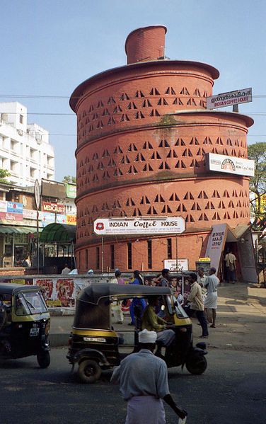 a tall brick building sitting on the side of a road next to a traffic filled street