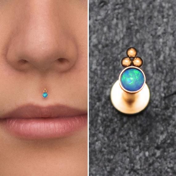 a woman's nose and nose ring with opal inlays on it