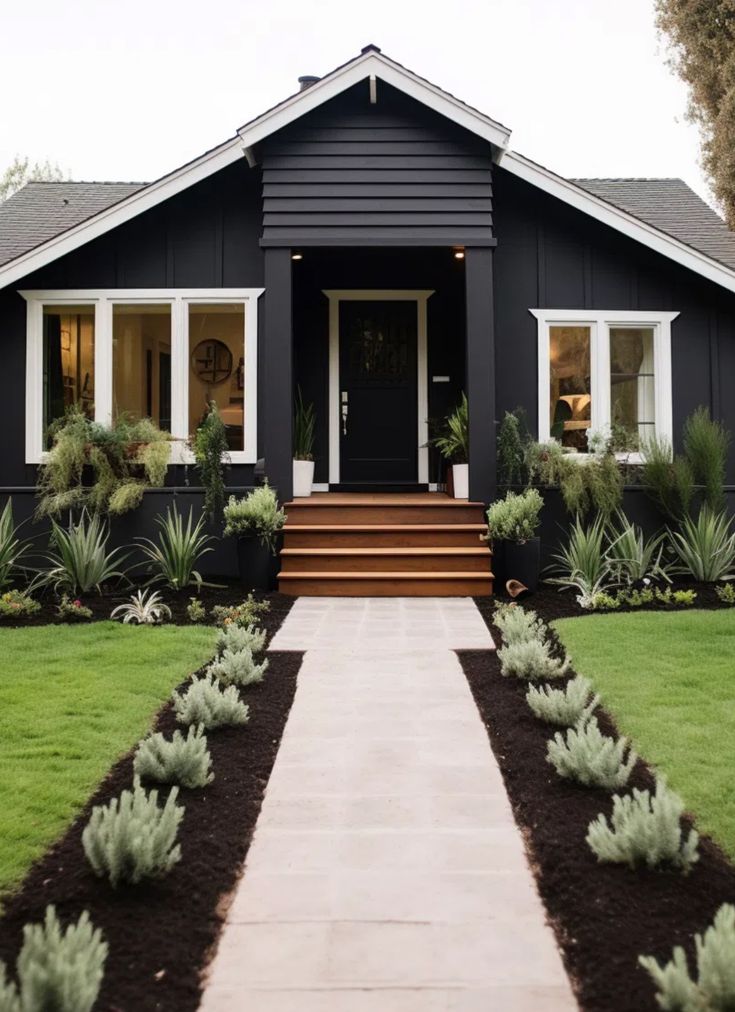 a black house with white trim and plants in the front yard, on a sunny day