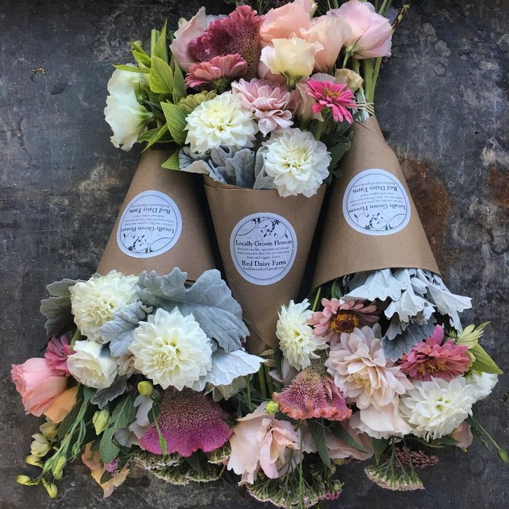 three cones filled with flowers sitting on top of a stone wall