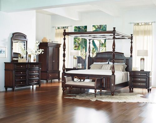 a bedroom with hardwood floors and white walls, including a four poster bed in the center