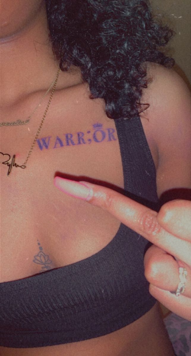 a woman with tattoos on her chest pointing at the camera