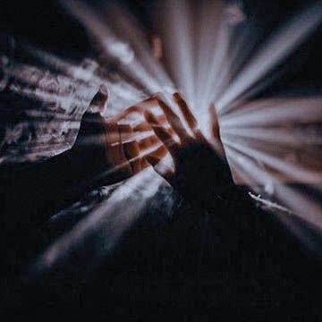 two hands reaching towards each other with light coming from behind them on a dark background