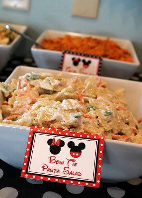 a table topped with bowls filled with pasta and veggies covered in mickey mouse's bow tie