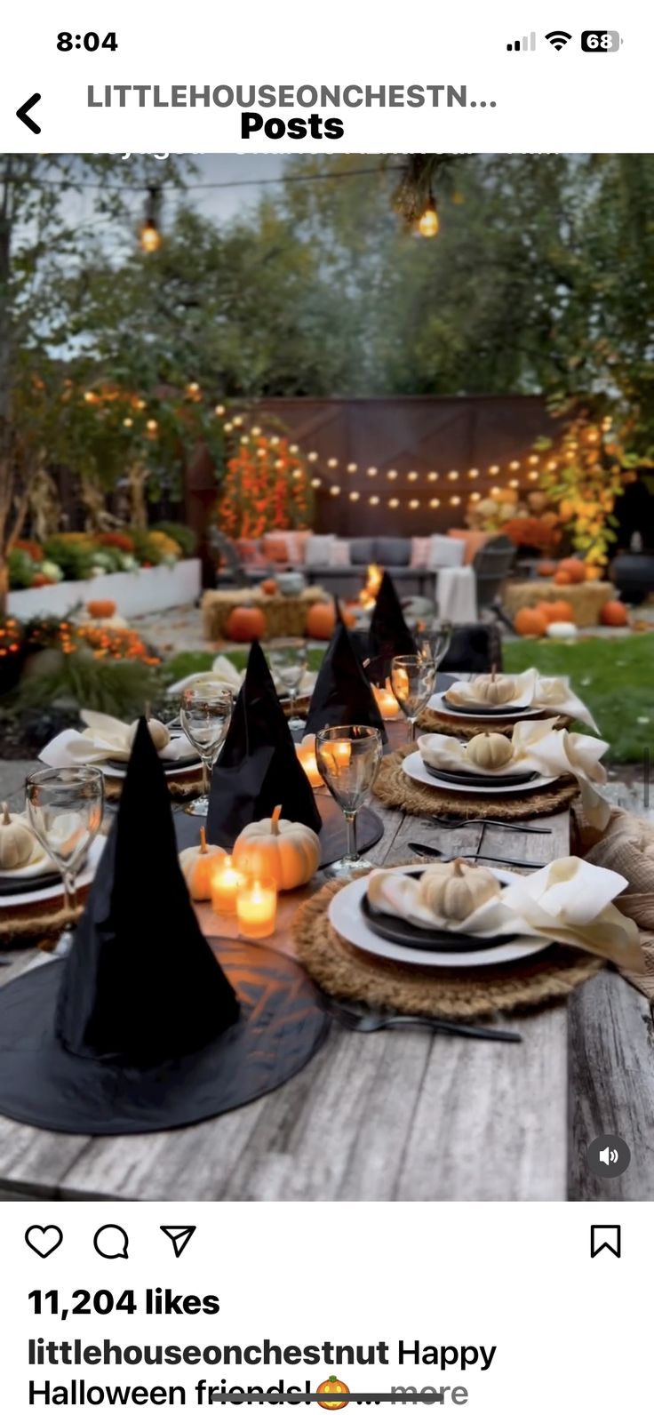 a wooden table topped with lots of plates and place settings covered in black witches hats