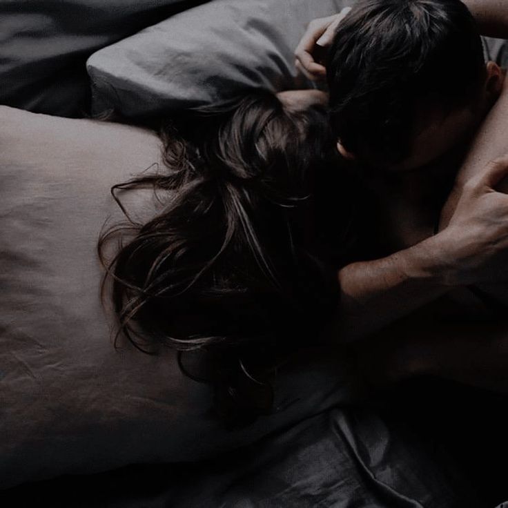 a man and woman cuddling on top of each other while laying in bed together