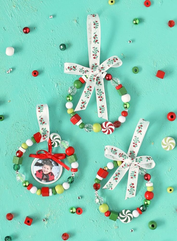 three christmas ornaments with candy and candies around them on a turquoise background, one has a small ornament hanging from it's side