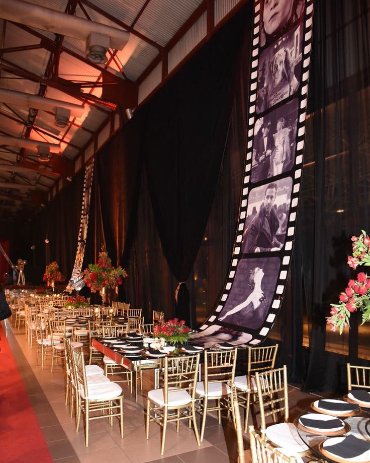 tables and chairs are set up in front of a black curtain with pictures on it