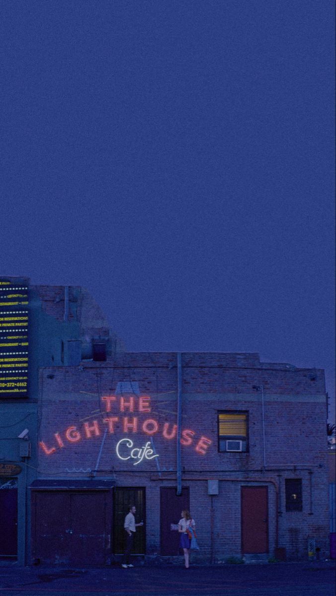 the light house cafe is lit up at night with neon signs on it's side