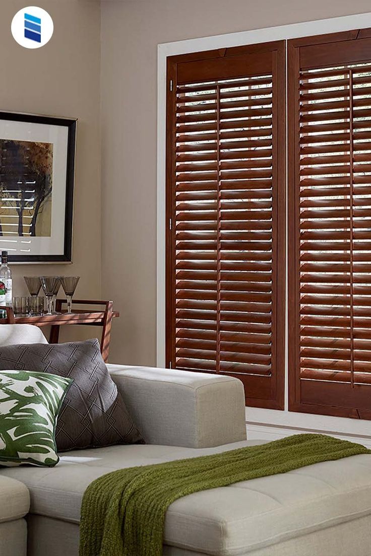 the living room is decorated in neutral colors and features wood shutters that match with the white sofa