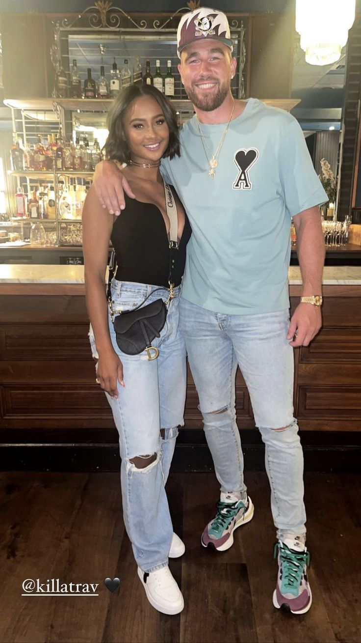 a man and woman standing next to each other in front of a bar with wooden floors