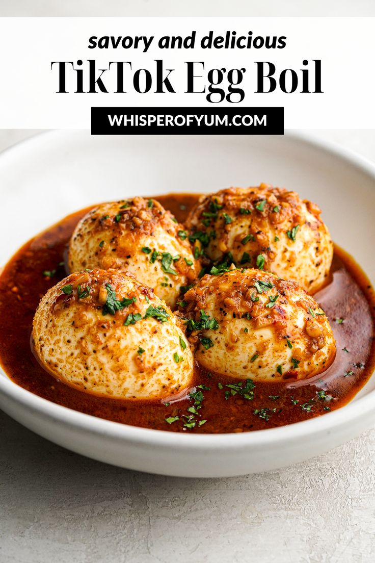 some food in a white bowl on top of a table with sauce and garnish