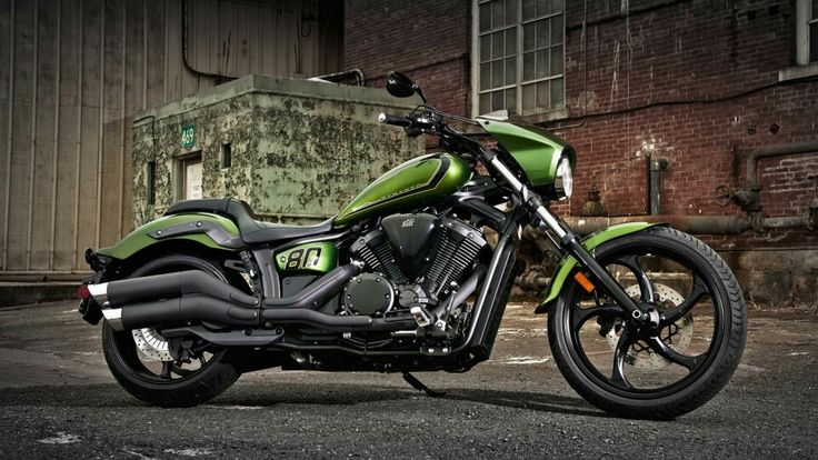 a green motorcycle parked in front of a brick building