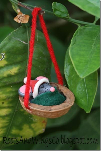 an ornament hanging from a tree in the shape of a mouse on a green leaf