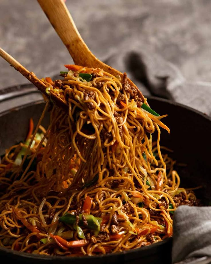 noodles being cooked in a wok with chopsticks