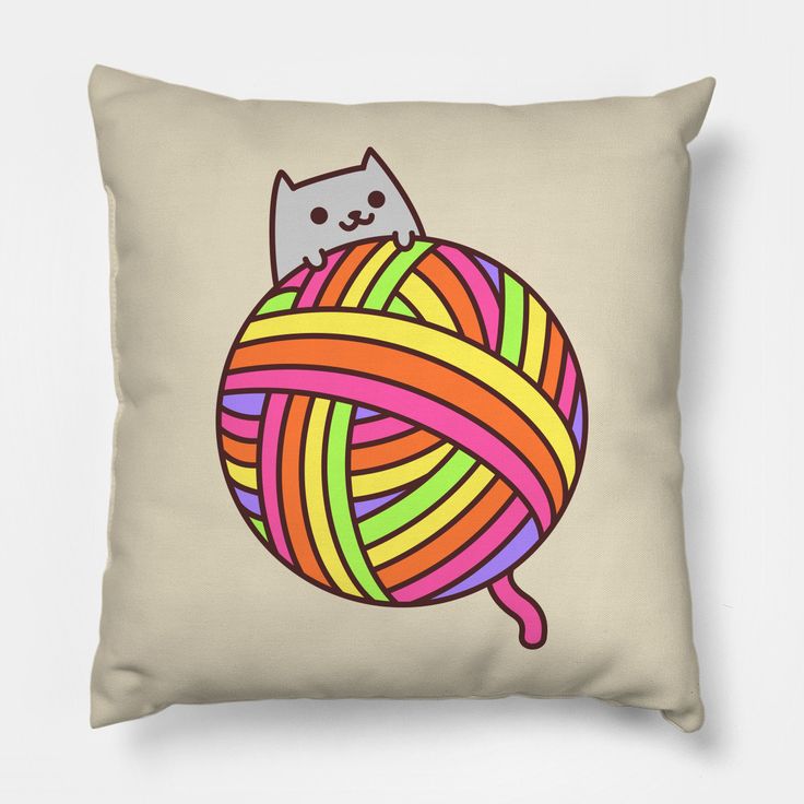 a pillow with a cat sitting on top of a ball of yarn in the shape of a ball