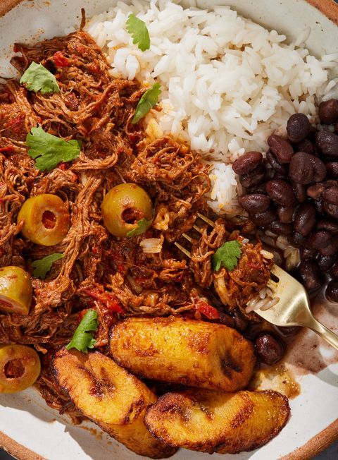 a white plate topped with meat, beans and rice