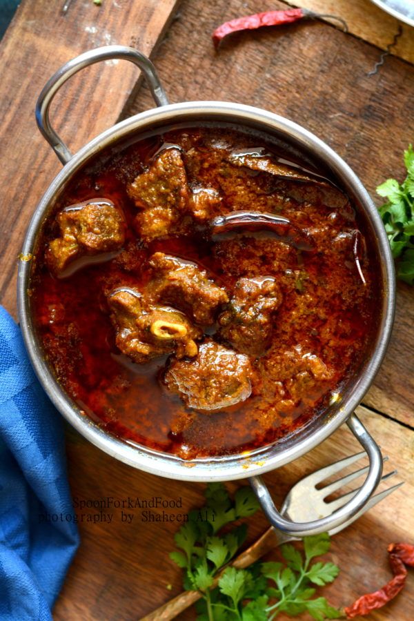 a pot filled with meat and sauce on top of a wooden table