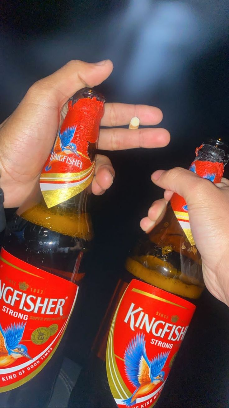 two people holding onto bottles of kingfish beer