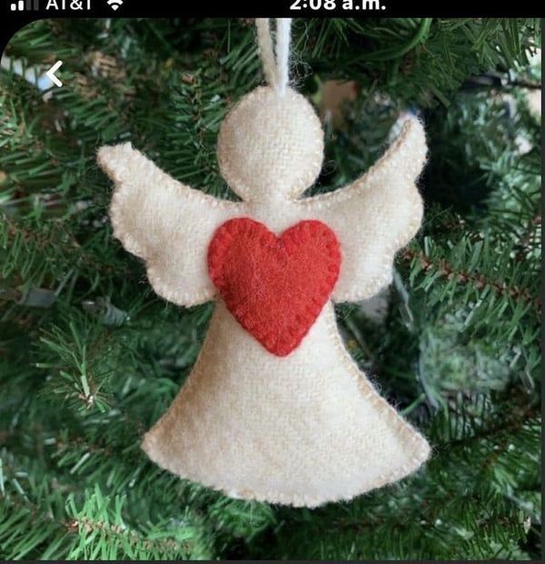 an ornament hanging from a christmas tree with a red heart on it's side