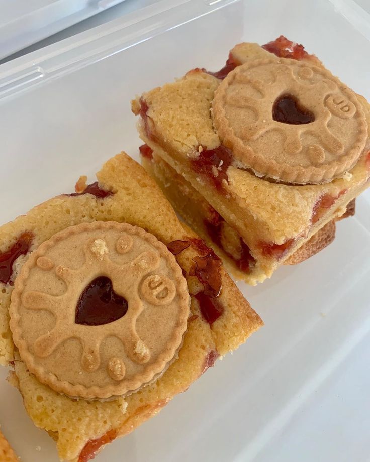 two pieces of cake sitting on top of a plastic container filled with jelly and peanut butter