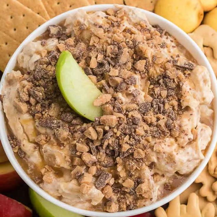 a white bowl filled with oatmeal and apple slices next to crackers