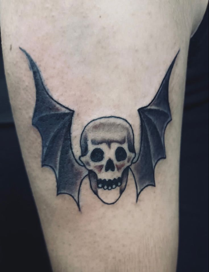 a skull and bat tattoo on the leg