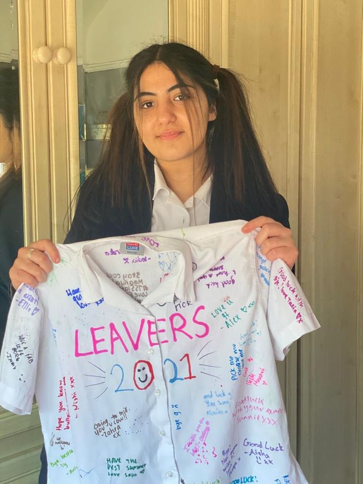 a woman holding up a white shirt with writing on it