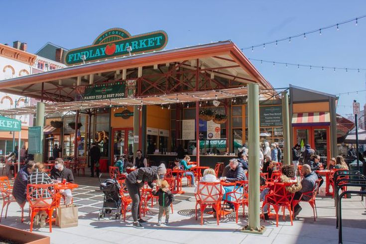 many people are sitting at red tables outside