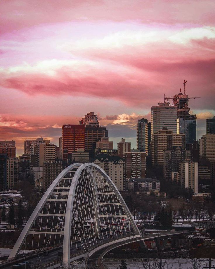 the city skyline is lit up with pink clouds