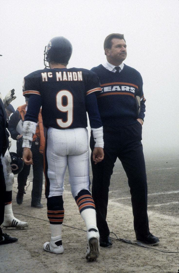 two football players are standing on the sidelines with their hands in each other's pockets