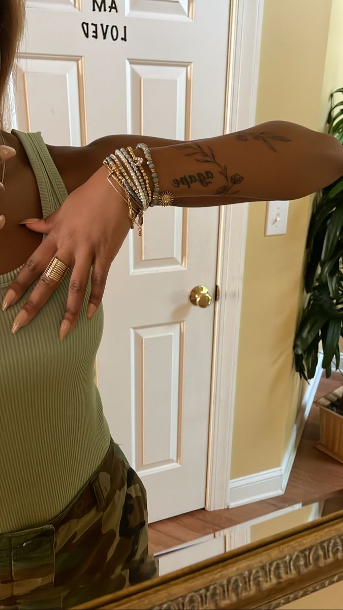 a woman with tattoos on her arm and arm bracelets in front of a mirror